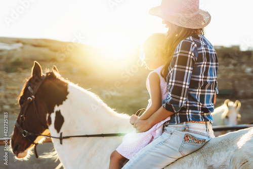 Happy family mother and daughter having fun riding horse inside ranch photo