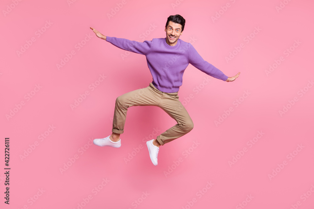 Photo of cute funny young man dressed purple pullover jumping arms wings isolated pink color background