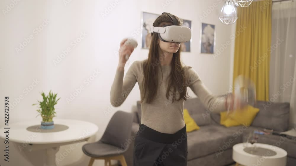 Fit young woman wearing VR headset swiping left and right with controllers playing games Fit young woman wearing VR headset swiping left and right with controllers playing games
