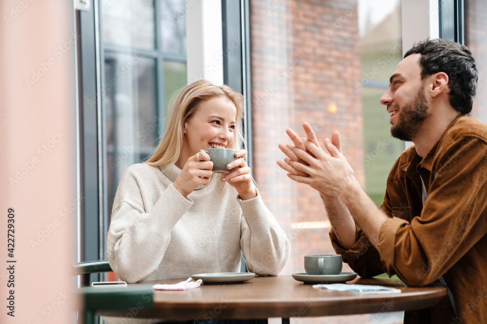 Young man and woman smiling and talking while drinking coffee in cafe Young man and woman smiling and talking while drinking coffee in cafe