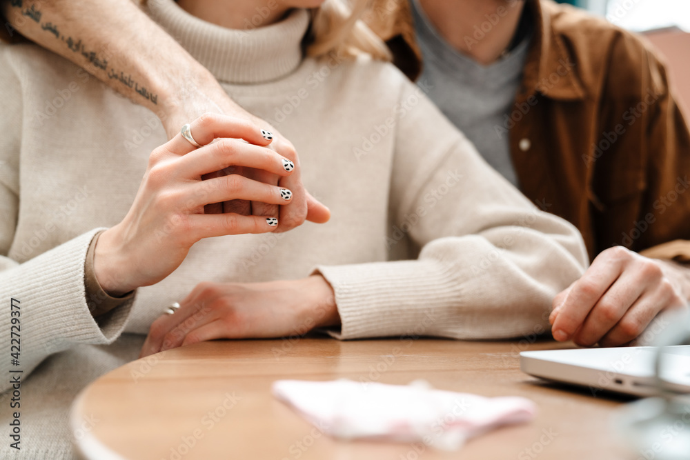 Couple hugging and using laptop while sitting in cafe Couple hugging and using laptop while sitting in cafe