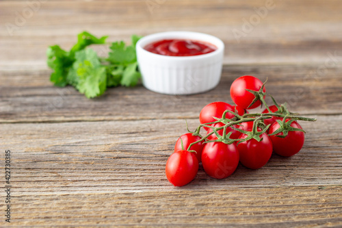 White bowl of tomato sauce with parsley and tomato. Ketchup on natural wooden background