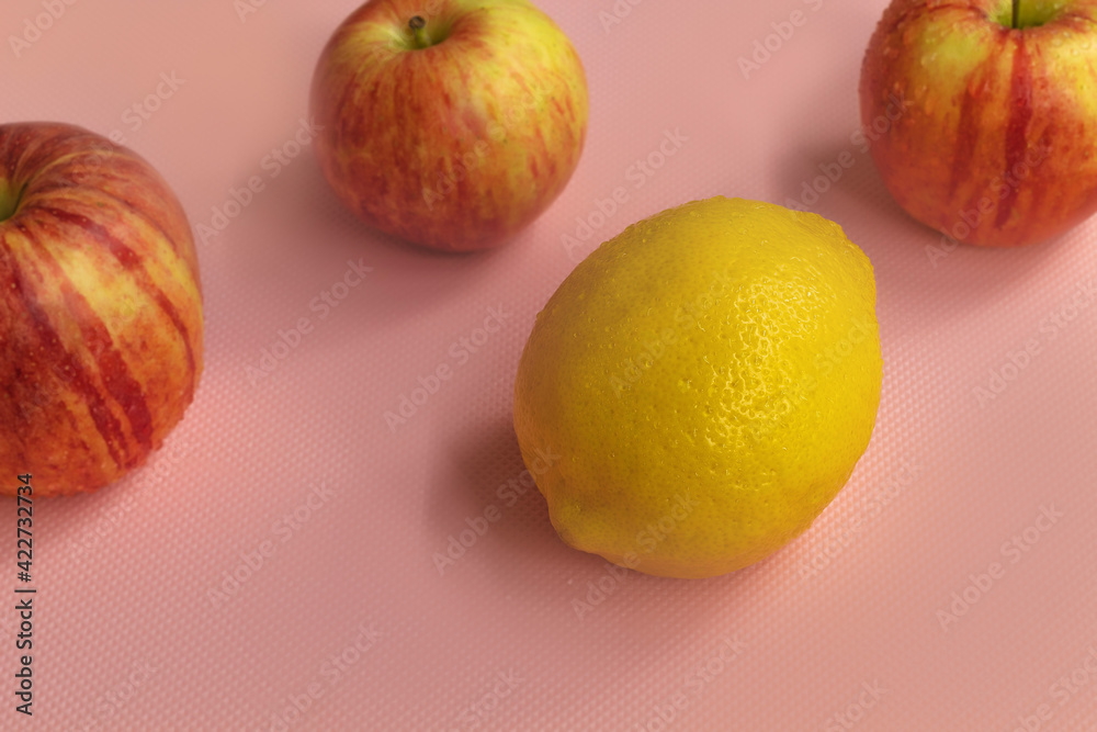 Fresh and ripe three gala apples with lemon in the center on a pink background Fresh and ripe three gala apples with lemon in the center on a pink background