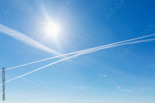 Airplane tracks and chemical trails in the clear blue sky.