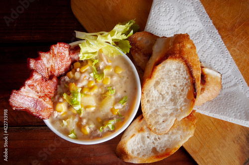 Corn chowder soup with bacon. Brown wooden background. Close-up view