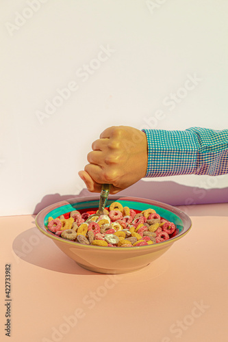 Arm of woman eating colors cereals with milk at vintage kitchen