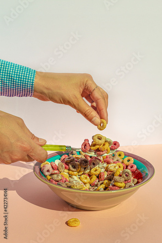 Arm of woman eating colors cereals with milk at vintage kitchen