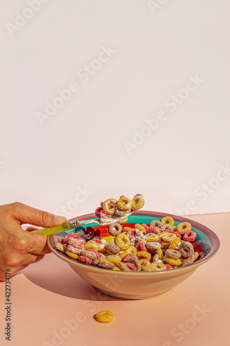 Arm of woman eating colors cereals with milk at vintage kitchen