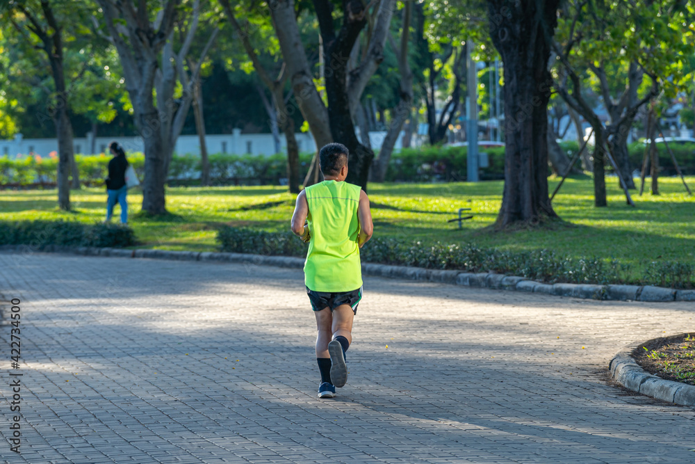 Asian man jogging at the park in sunny morning