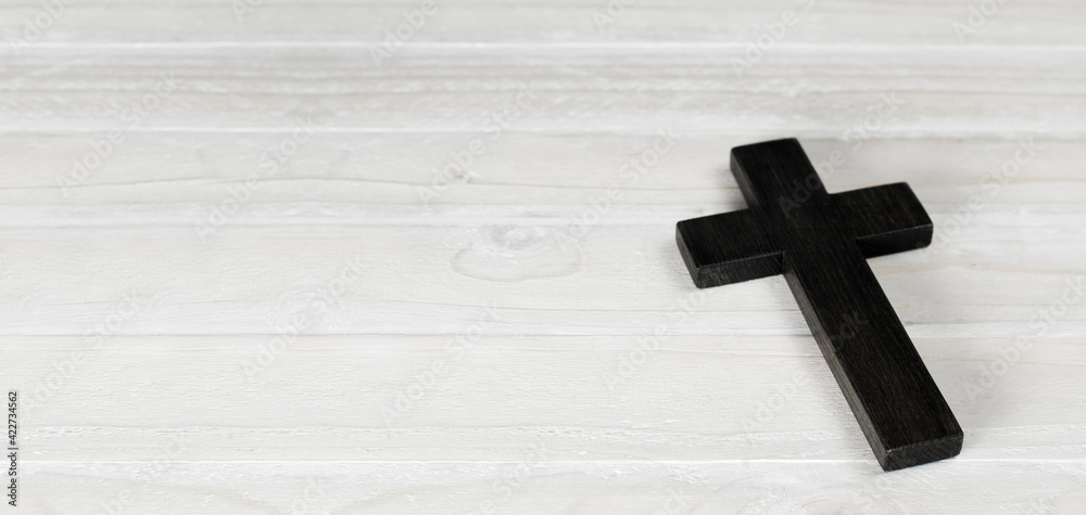 Wooden cross of Jesus. On a wooden white background. Death symbol. Religious christian