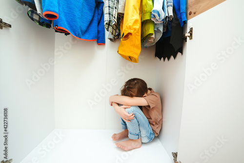 Photo Sad boy hiding in the wardrobe