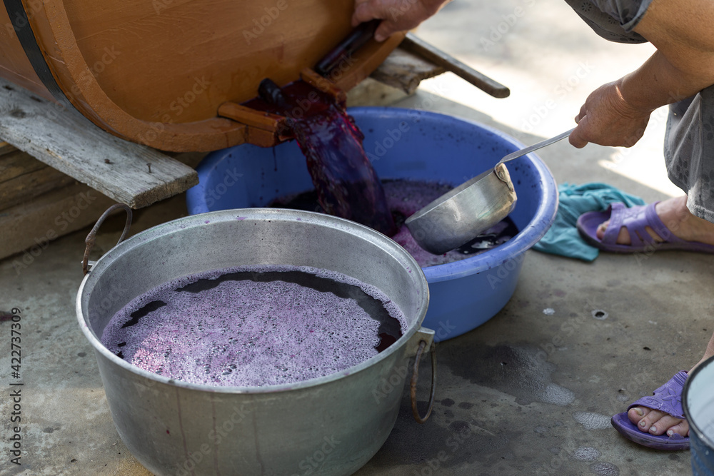 The winemaker pours grape juice for transportation into barrels. The winemaker pours grape juice for transportation into barrels.