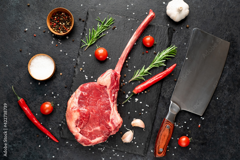 raw tomahawk beef steak with spices on stone background
