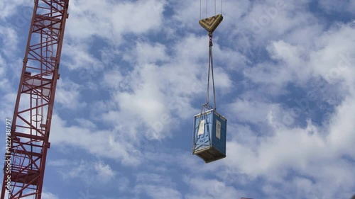 The mobile toilet is lifted by the crane on the construction site.