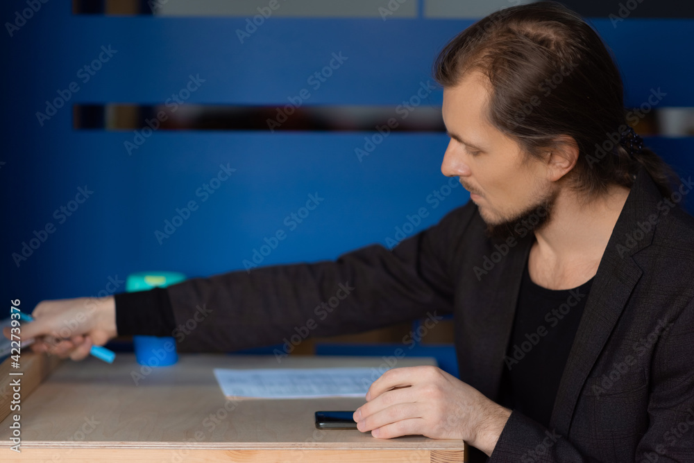 Businessman takes a new sheet for taking notes from the phone Businessman takes a new sheet for taking notes from the phone