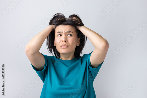 Portrait of attractive lady holding hands on head. Human face expressions and emotions.