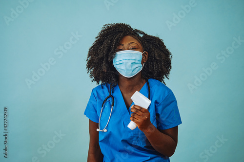 Nurse practitioner doctor with face mask and temperature measure infrared gun