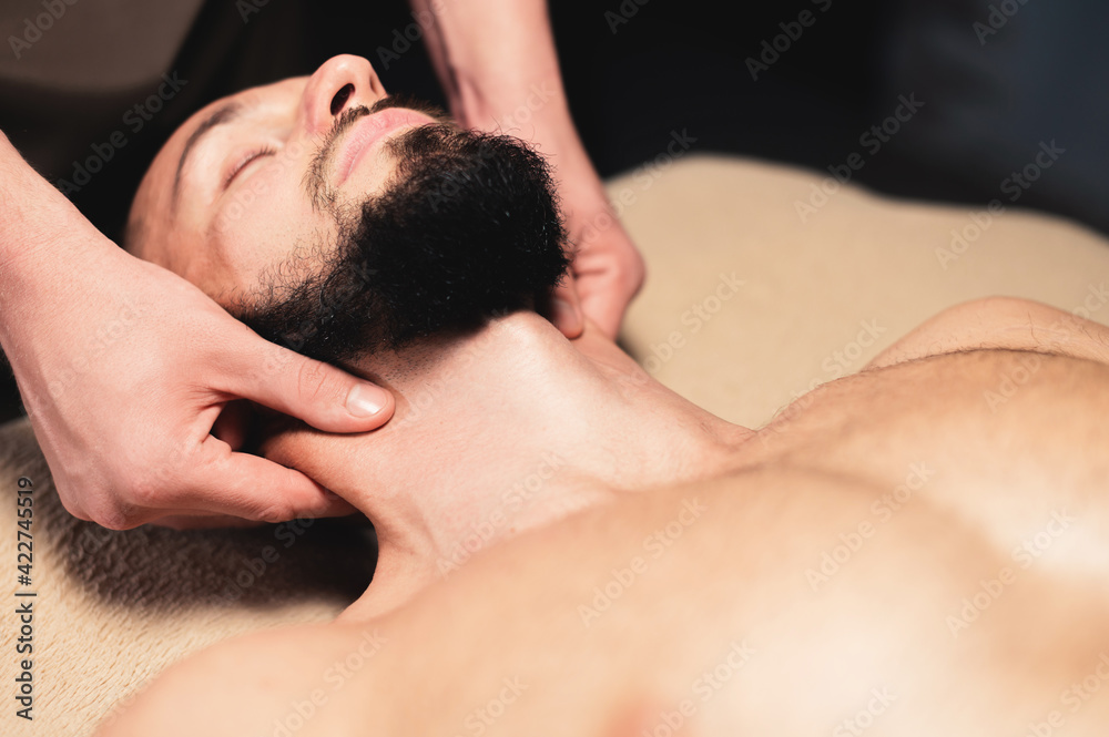 Close-up Professional neck massage to a bearded male athlete in a dark room of a spa massage room Close-up Professional neck massage to a bearded male athlete in a dark room of a spa massage room