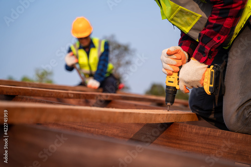 Foto Close up roofer working on roof structure of building on construction site, Roofer using air or pneumatic nail gun and installing on wooden roof structure