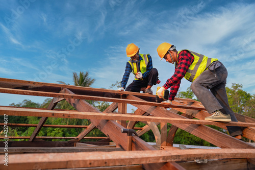 Asian construction worker install new roof, Roofing tools, Electric drill used on new roofs of wooden roof structure, Teamwork construction concept.