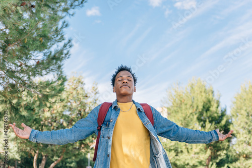 Relaxed dark skinned boy takes air in the street