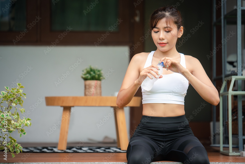 Asian young woman drinking water after workout exercising.