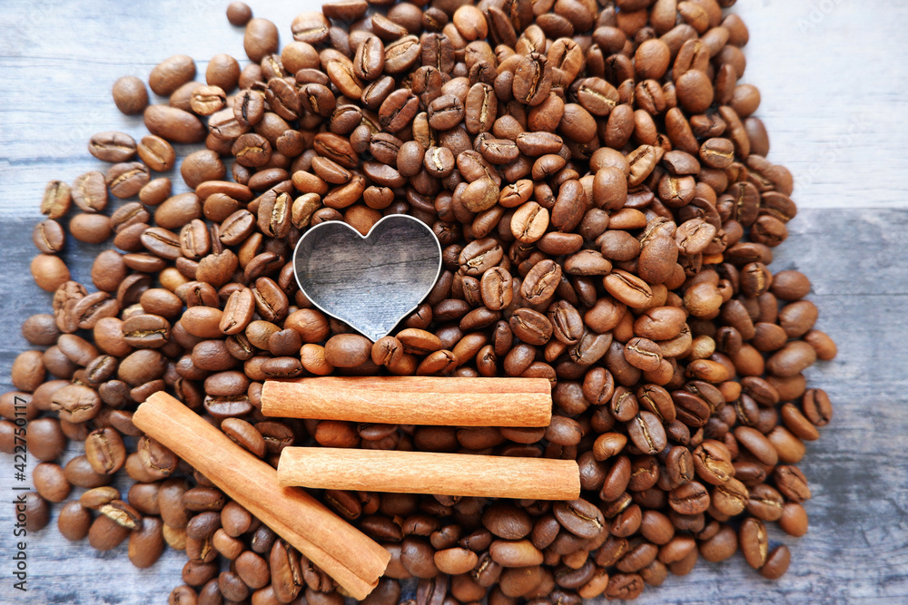Obraz premium Love coffee concept. Coffee beans, cinnamon sticks and Heart symbol on a vintage dark wooden background for cafe menus, brochures and event design. コーヒー豆とシナモンスティック、カフェイベント、コーヒーデザイン背景