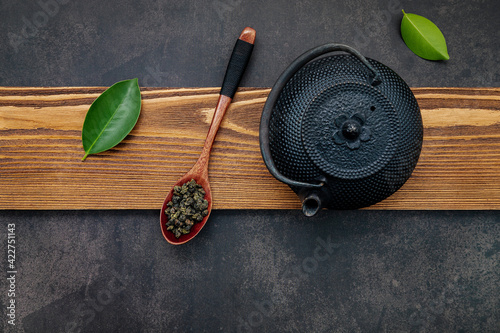  Black cast iron tea pot with herbal tea set up on dark stone background.