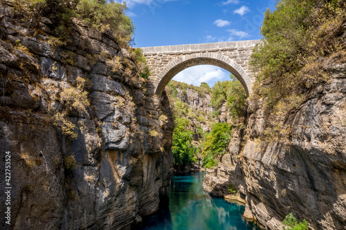 Ancient arch bridge Oluk over the Koprucay river gorge in Koprulu national Park in Turkey. Panoramic scenic view of the canyon and blue stormy mountain river photo