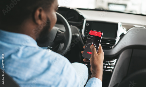 Cashless technology or digital payment for fuel energy. Black guy using mobile app to buy petrol online inside his car © Prostock-studio