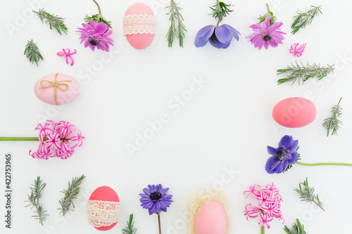 Ester frame made of eggs, spring flowers and leaves of lavender on white background. Flat lay
