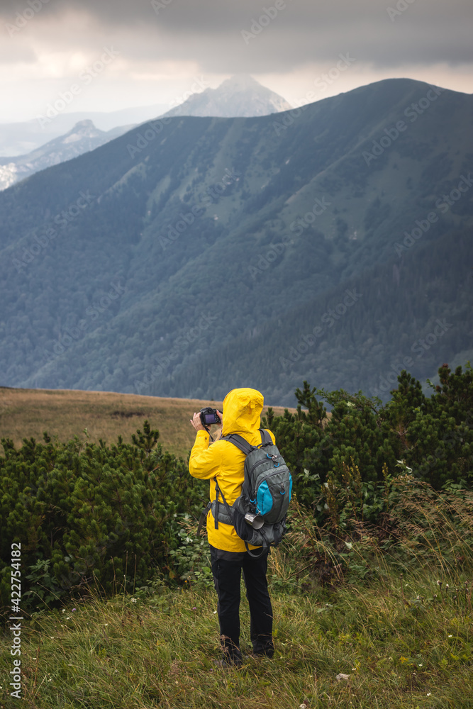 Tourist with camera taking picture of landscape during hiking in mountains. Woman with backpack trekking in natural parkland Mala Fatra, Slovakia