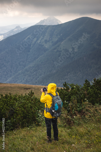 Tourist with camera taking picture of landscape during hiking in mountains. Woman with backpack trekking in natural parkland Mala Fatra, Slovakia