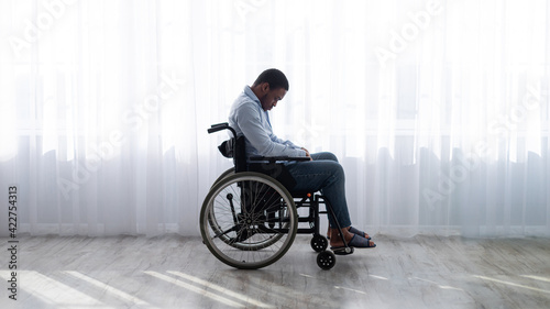 Fotografie Full length of handicapped black man in wheelchair feeling desperate and lonely,