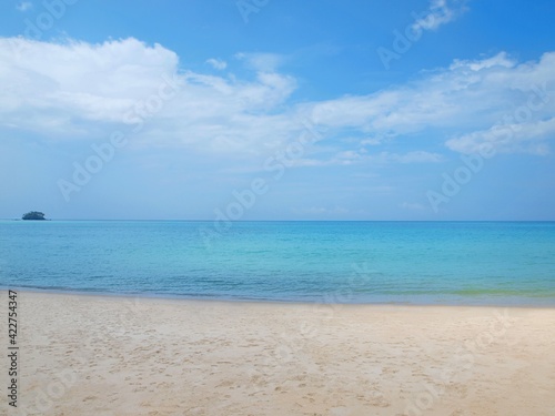 Tropical beach. Sandy coast. Sea view. Blue sky with clouds. Small green island on the horizon. Empty shore. Summer resort. Azure calm water. Bright colors of ocean. Panorama  horizontal frame. Phuket