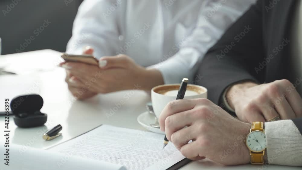 woman explains a business idea to a colleague, shows something on a smartphone, sits in a cafe, talks, in formal clothes, business cooperation, brainstorming. woman explains a business idea to a colleague, shows something on a smartphone, sits in a cafe, talks, in formal clothes, business cooperation, brainstorming.