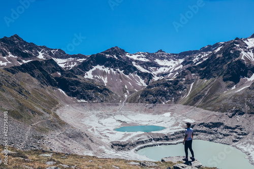 boy with an athletic figure standing over the drained Finstertal dam near the village of Kuhtai in western Austria, near famous Innsbruck. View of mountains Sulzkogel, Gamskogel