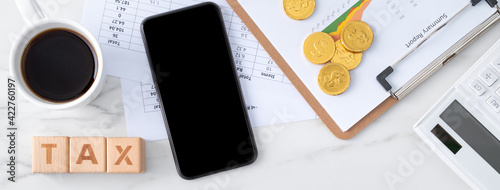 Fotografija Top view of calculating and paying tax with smart phone on white table