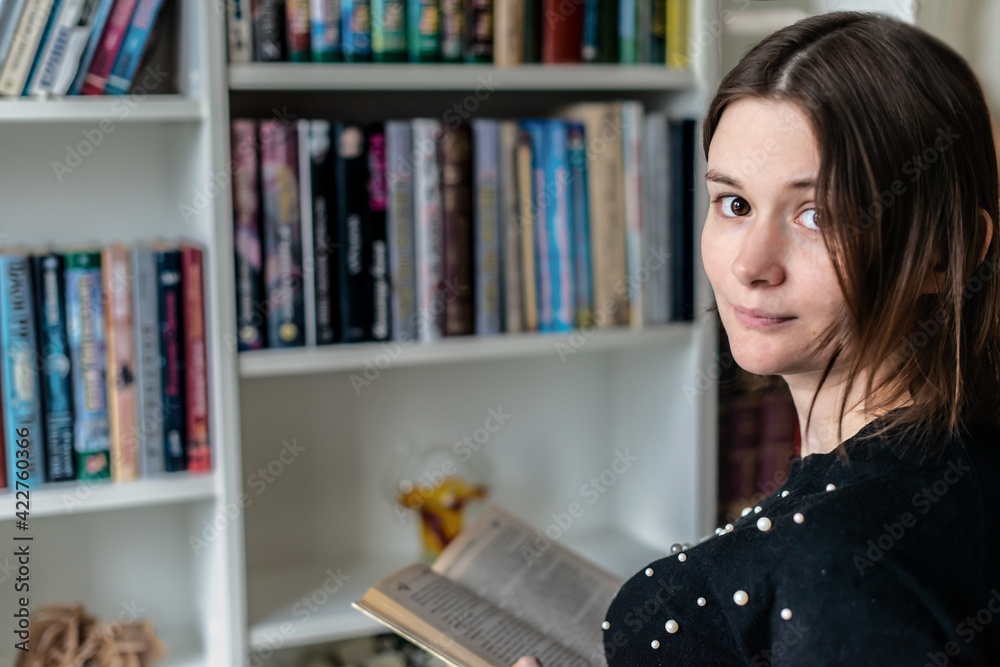 Beautifull woman reading book in library looking at camera and smiling Beautifull woman reading book in library looking at camera and smiling