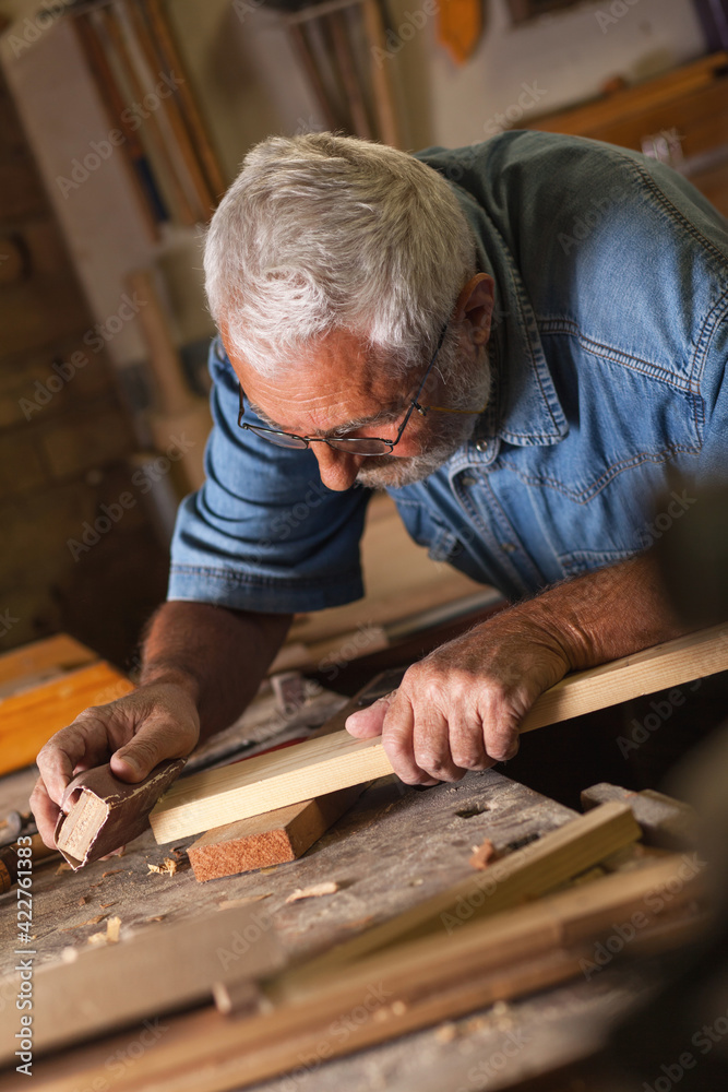 Experienced carpenter working in his old fashioned workshop.Working with sand paper. Experienced carpenter working in his old fashioned workshop.Working with sand paper.