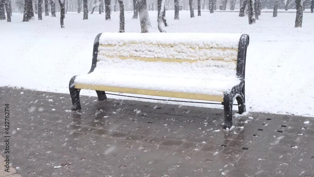 city park bench under heavy snowfall by winter
