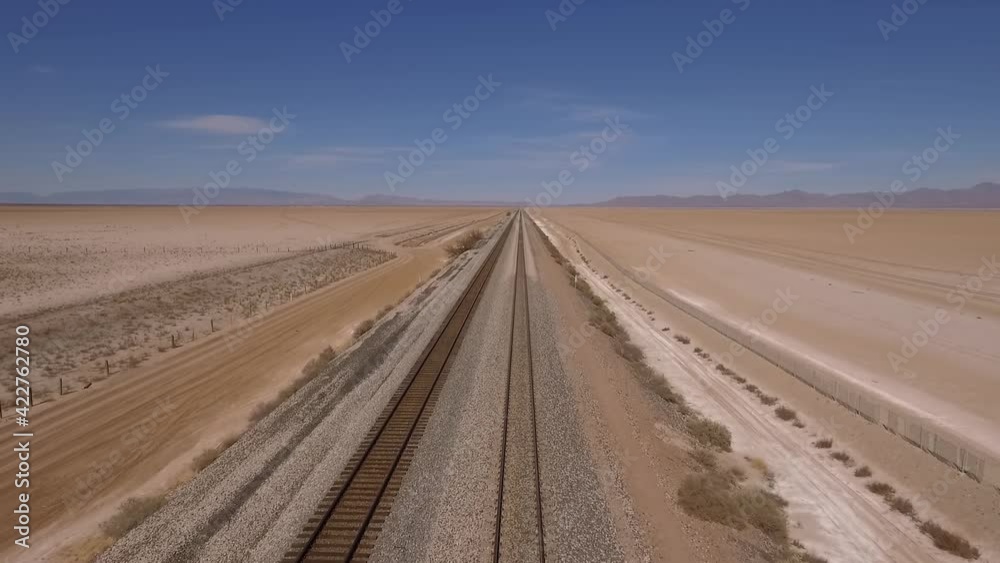 Aerial of train tracks leading off into the distance on a desert dry lake Aerial of train tracks leading off into the distance on a desert dry lake