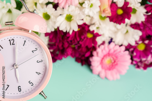 Spring is comming! Pink watch with colorful flowers on a green background.