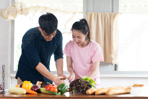 Asian young couples are cutting vegetables and smiling while cooking in kitchen at home