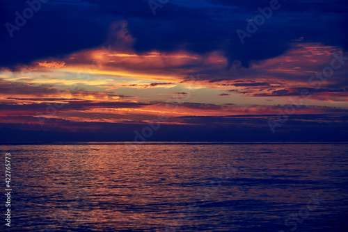 Beautiful cloudy sky at dawn, calm sea water. © Pavlo