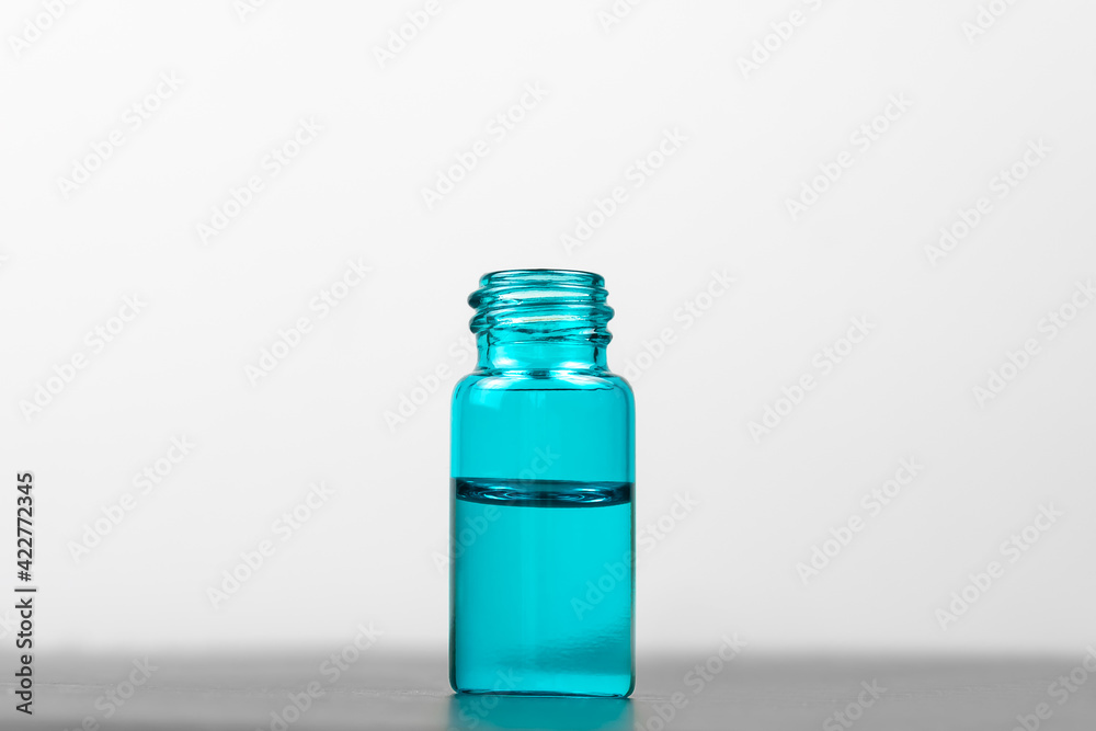 Close-up of a turquoise serum bottle on a white background copy space. Concept of cosmetology, medicine
