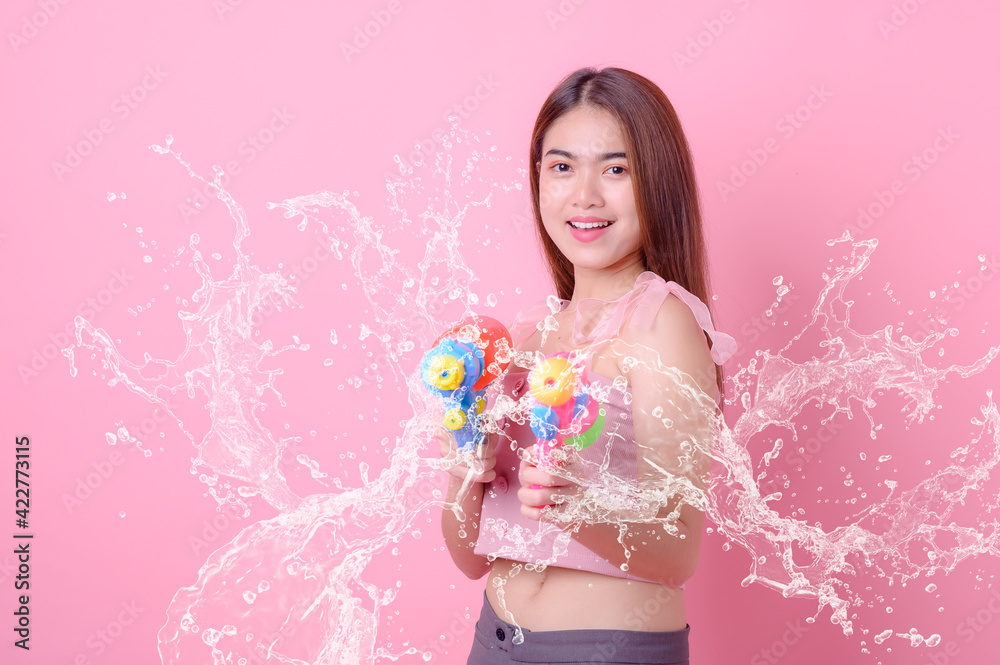 A beautiful Asian woman shows a gesture while holding a plastic water gun during the Songkran festival A beautiful Asian woman shows a gesture while holding a plastic water gun during the Songkran festival