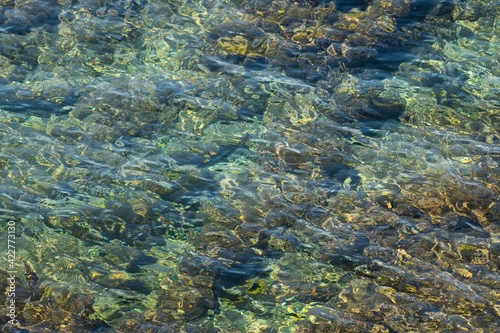 rippled water surface and stone ground at the Mediterranean sea in abstract close up