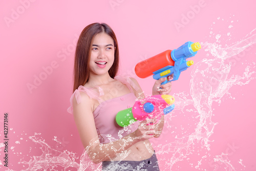 A beautiful Asian woman shows a gesture while holding a plastic water gun during the Songkran festival