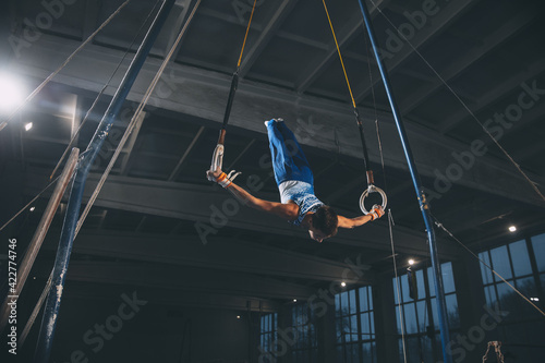 Little male gymnast training in gym, flexible and active. Caucasian fit little boy, athlete in sportswear practicing in exercises for strength, balance.